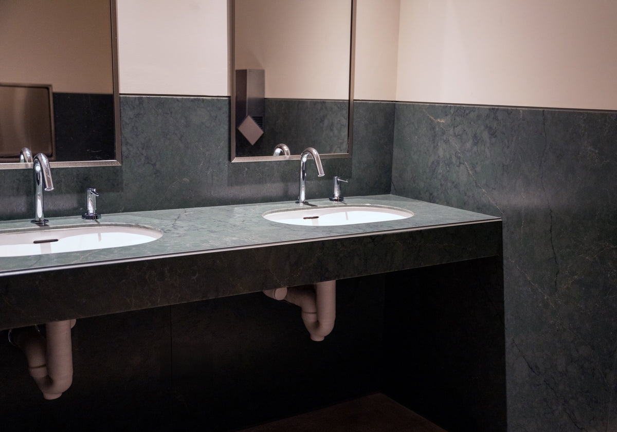 Green stone restroom vanity at Erewhon with a LUSTRO® metal edge